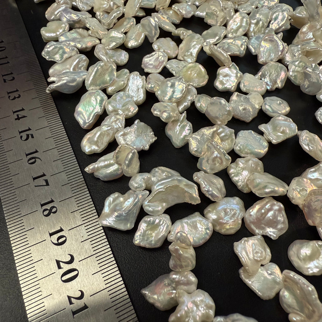 Baroque pearls with a ruler for scale on a dark background